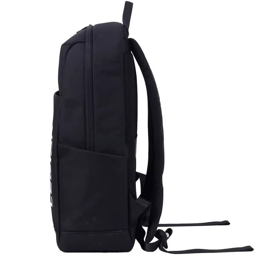 Rear view of the backpack secured onto the telescoping handle of a rolling suitcase using its integrated luggage strap, showing the breathable mesh back panel.