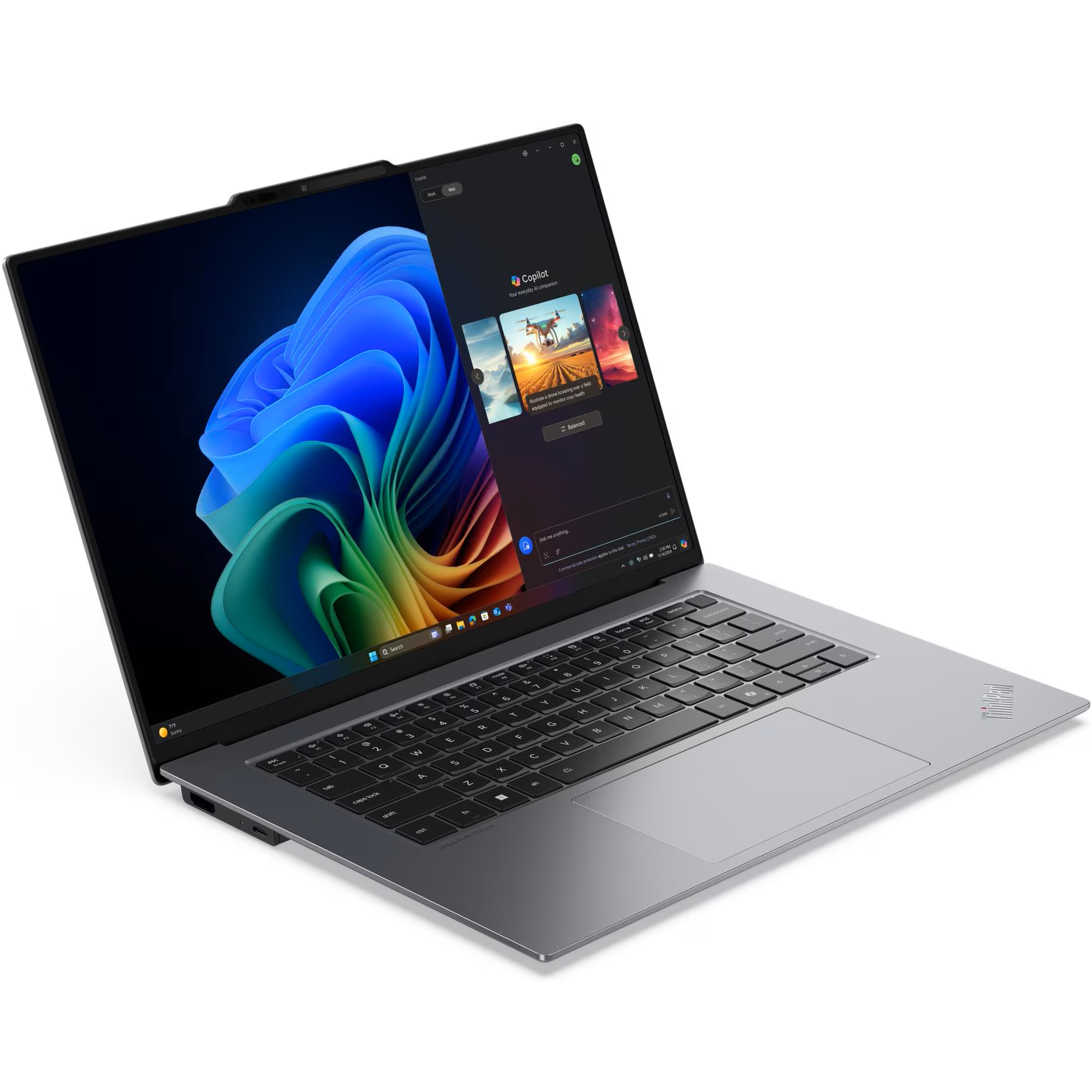 Front-left angled view of the open Lenovo ThinkPad X9-15 Gen 1 AURA Edition showcasing its slim graphite chassis, keyboard deck, wide touchpad, and 15.3-inch 2.8K 120Hz OLED screen displaying Windows 11 and Microsoft Copilot.
